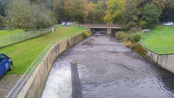 Das Wasser fließt die Agger hinab. Es wird darauf geachtet, dass möglichst wenige  Sedimente mit weggeschwemmt werden.