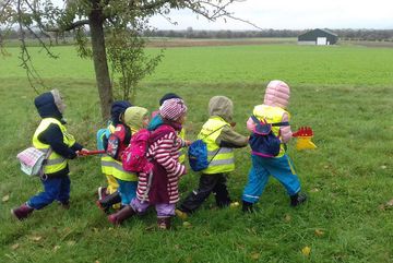 Eine Kindergruppe des NaturErlebnis-Werkstatt in Alsdorf unterwegs auf der Wiese. 