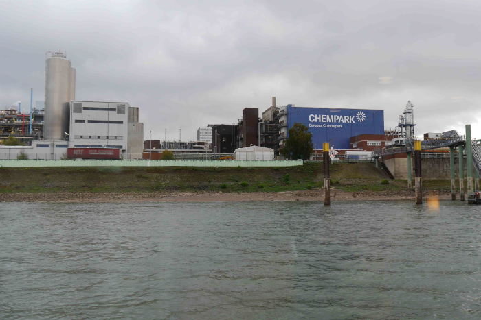 Der Currenta - Chempark vom Rhein aus gesehen - täglich fließen von hier aus ca. 140.000 Kubikmeter behandeltes Abwasser in den Fluss, im Jahr über 50 Millionen, in etwa soviel, wie die ganze Stadt Köln an Trinkwasser gebraucht. 